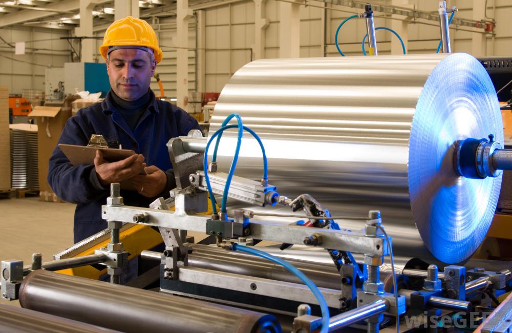 man looking at clipboard and standing next to a machine